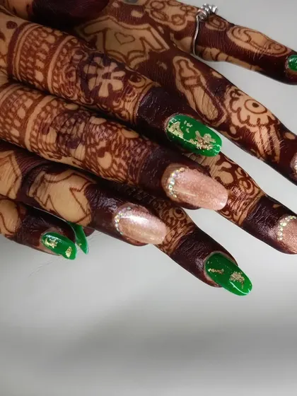 A unique bridal nail design combining a neutral shimmery base with bold green accent nails, complete with gold foil and rhinestone details.