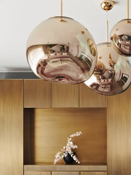 A close-up of the rose-gold pendant lights in the Maximum City Duplex. The reflective, sculptural forms add a touch of glamour and serve as a focal point in the living space.