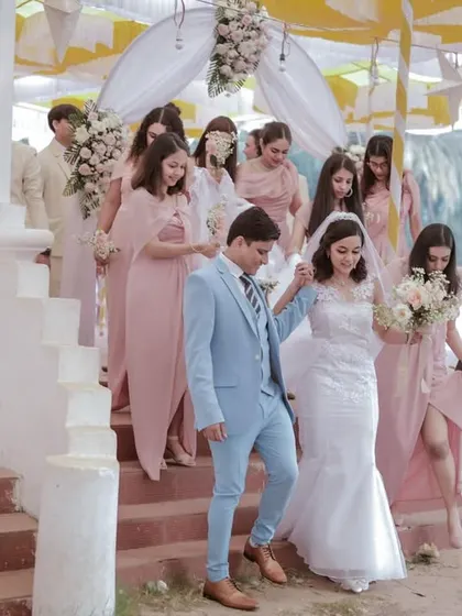The bride and groom making their way down the stairs with the bridesmaids. A beautiful, candid moment from a Catholic wedding in Goa.