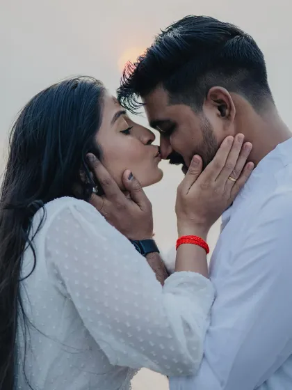 An intimate close-up of a couple sharing a gentle kiss during their beach pre-wedding shoot, their faces framed by their hands.
