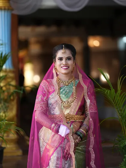 A classic portrait of the bride in her gorgeous silk saree and pink veil, ready for her wedding ceremony.