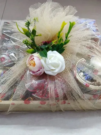 This Gourmet Treats Basket is a great example of lavish gifting. The items are arranged in a flat tray, wrapped in delicate netting, and topped with a floral arrangement.