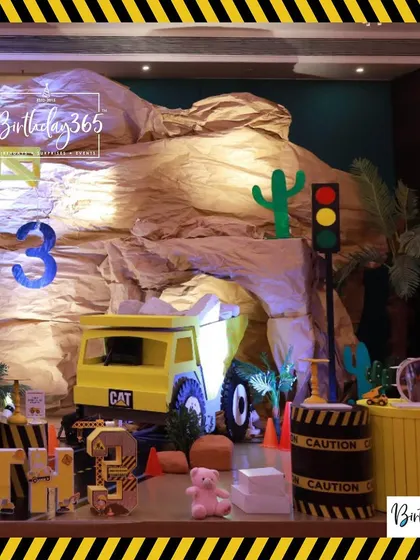 A wide view of the construction site we built for Mihith's 3rd birthday, complete with a large dump truck, a rock cave, and caution-themed decor.
