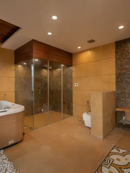 The second floor of the Ashraya Residence is dedicated to recreation, featuring this spacious spa room with a shower and whirlpool bathtub. The flooring is finished in Khareda stone with a mosaic design, adding a rich, tactile character.