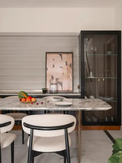 A close-up of the custom dining table and chairs. The combination of the patterned marble, soft upholstery, and black accents redefines modern dining elegance.