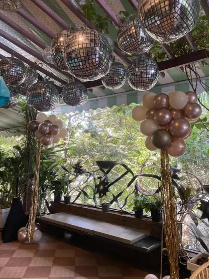 A closer view of the disco ball and balloon columns for the 60th birthday celebration. The mix of metallic and neutral-colored balloons with shimmering tassels creates a fun yet sophisticated party atmosphere.