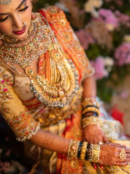 A close-up on Jhanvi's opulent bridal look. This shot highlights the incredible detail of her layered jewelry and the rich, multi-colored embroidery on her custom blouse.
