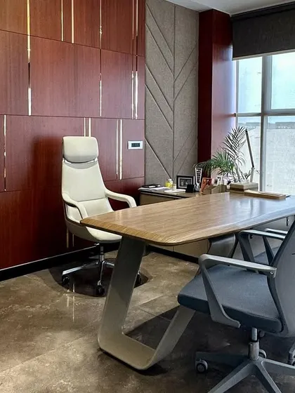 A side profile of the executive office, highlighting the unique Z-shaped leg design of the desk and the high-back leather chair. The design focuses on modern forms and high-quality materials.