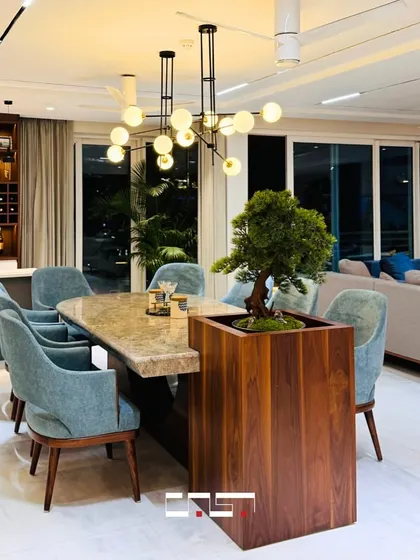 An open-plan living and dining area where a custom dining table with a built-in planter serves as a unique centerpiece, seamlessly blending the two zones.