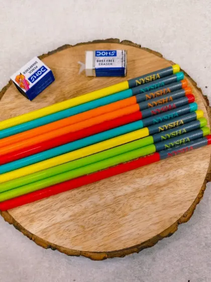 A set of colorful name-engraved pencils, displayed on a wooden platter. These make great return gifts for birthday parties.