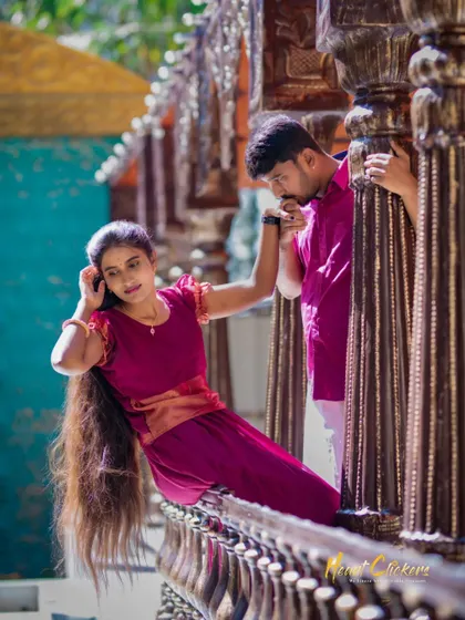 A classic, regal pose on an ornate wooden balcony. The groom kisses the bride's hand, creating a moment of chivalry and romance.