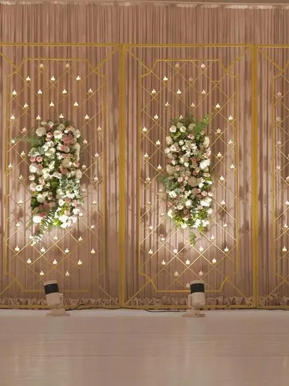 The beauty of minimalistic decor is showcased in this stage design, with simple gold frames, delicate floral bunches, and a backdrop of hanging lights.