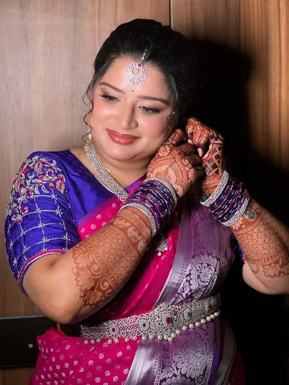 A getting-ready shot, as the bride puts on her earrings. The makeup is complete, featuring a soft smokey eye and a glossy nude lip.
