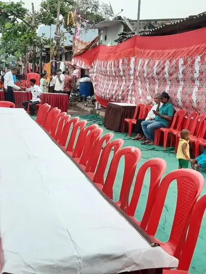 A long dining table setup with chairs for a community feast (bhandara).