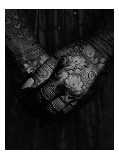 A dramatic black and white close-up of a bride's hands, showcasing the intricate patterns of her mehendi.