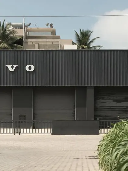 A street-level view of the Volvo Vehicle Tech Lab. The building's minimalist, dark facade presents a clean and modern identity. Surrounded by native plants, it demonstrates how industrial facilities can be designed with a focus on green principles and a minimal carbon footprint.