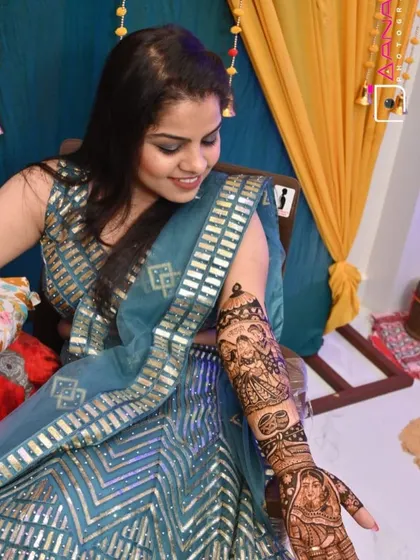 A happy bride showing off her custom portrait mehandi. The design includes a couple's portrait and other personal elements.