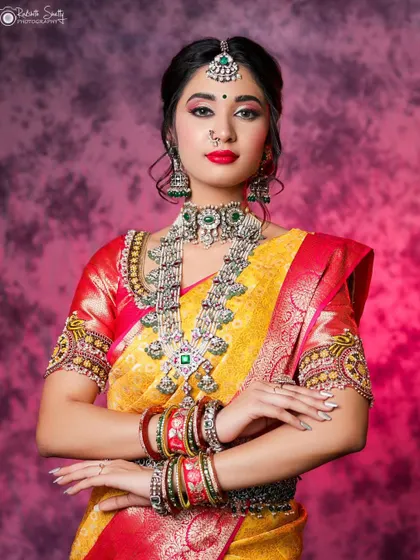 A beautiful portrait of a model in a yellow and red silk saree. The vibrant colors and her confident pose against a textured backdrop make this a stunning example of traditional fashion photography.