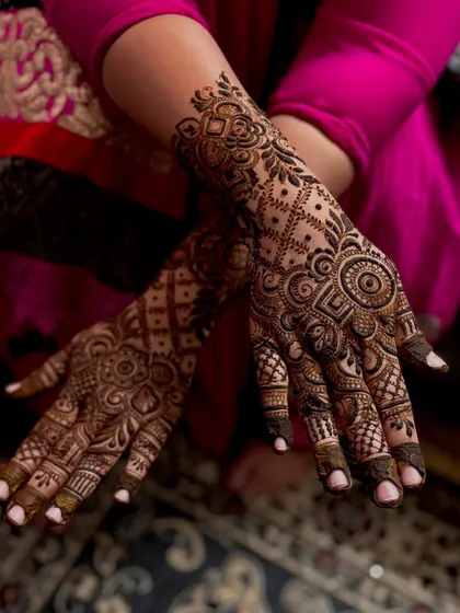 A crossed arm pose showing off this beautiful guest henna design. The patterns are symmetrical and create a stunning visual effect.