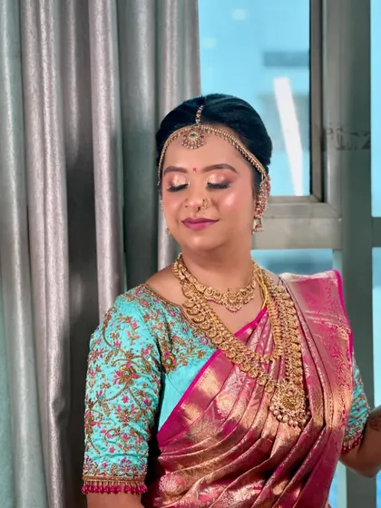 A beautiful portrait of a bride on her wedding day. Her hair is in a classic updo, adorned with a matha patti, showcasing a timeless and elegant bridal style.