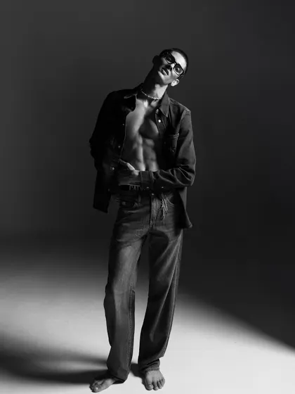 A dynamic full-length pose in black and white. The lighting creates a dramatic silhouette, showcasing the entire outfit while maintaining an artistic, editorial feel.