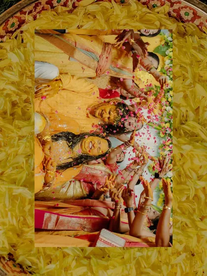 An artistic, top-down shot of the couple and their family covered in turmeric and flower petals, creating a beautiful, textured image full of joy.