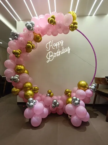 A half-arch balloon ring in pink, gold, and silver, with a neon sign. This design is great for smaller spaces or corners.