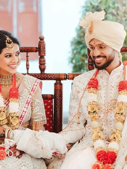 The couple seated on a traditional swing (jhoola) during their wedding, sharing a happy, relaxed moment.