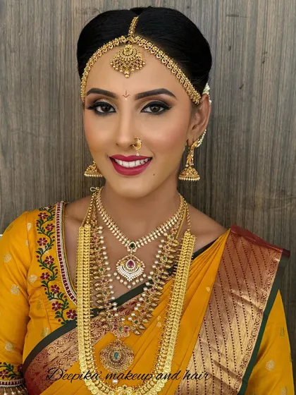 This bride's look for her big day features a vibrant yellow saree with a red border, complemented by classic gold jewelry and a bold red lip.