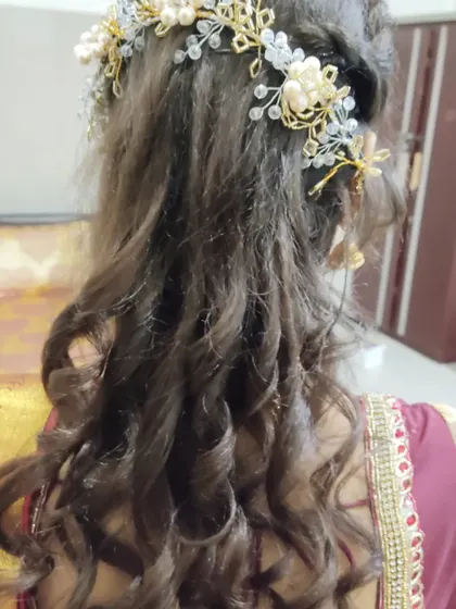 Tight spiral curls in a half-up style. This look is adorned with a beautiful gold and pearl hairpiece, perfect for a bride or bridesmaid.