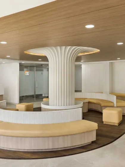 This waiting area at SPS Hospital Clinic in Ludhiana features a central sculptural column and curved seating. The design is a catalyst for healing, using organic forms and warm materials to create a non-clinical, comforting atmosphere.