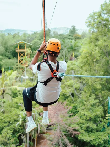 A guest gets a stunning view of the resort grounds while gliding on the zipline. It's an adventure that combines speed, height, and beautiful scenery.