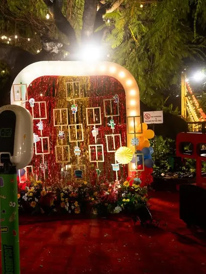 A fun "Strike a Pose" photo booth at a carnival-themed party. The setup includes a backdrop of framed photos and a red bus prop, providing a fun and interactive spot for guests.