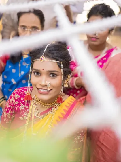 A creative shot of the bride looking through a part of the wedding decor, her happy face framed beautifully.