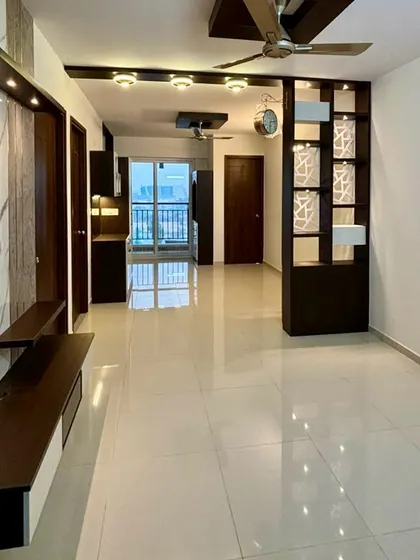 A wide shot of a completed living room, showing the sleek TV unit, a stylish partition, and a clear view towards the balcony, creating a bright and spacious feel.