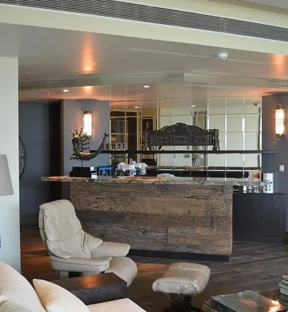 A different angle of the Magnolias living room, showing the open-plan layout. The reclaimed wood bar unit serves as a beautiful and functional divider between the seating area and the rest of the space.