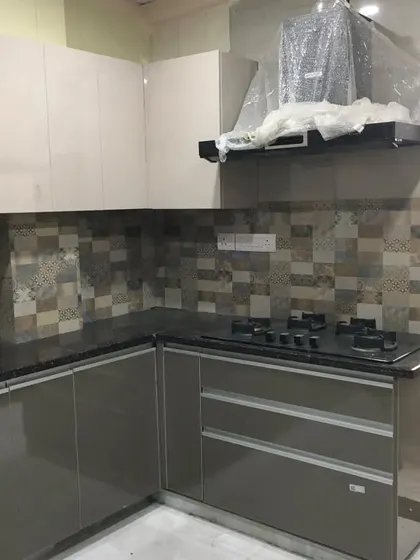 An L-shaped view of the delivered grey and white kitchen, showing the placement of the chimney and hob. The design ensures an efficient workflow for daily cooking.