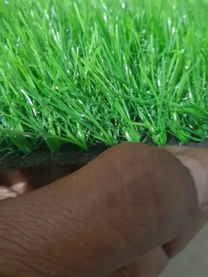 A close up showing the thickness and texture of a 25mm artificial grass sample. You can see the individual blades and the sturdy backing that holds them in place.