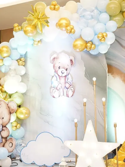 A close-up of the naming ceremony decor, featuring adorable teddy bear cutouts and a soft, pastel balloon arch.