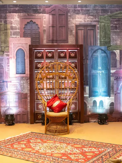 A throne fit for a Mehndi queen. The peacock chair is set against a creative backdrop of printed doors and windows, creating an eclectic and artistic photo corner.