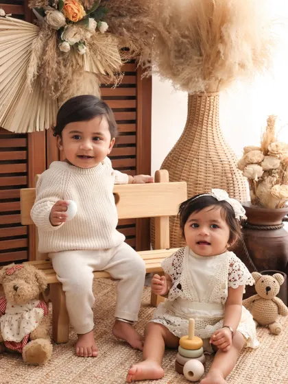 Two little best friends. This shot of the twins sitting on a bench surrounded by teddy bears and boho decor is incredibly sweet and highlights their special bond.