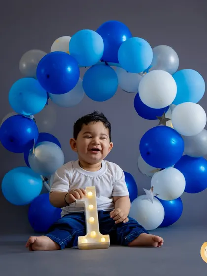 A joyful first birthday portrait with a classic blue and white balloon wreath. This setup is perfect for capturing that big, happy grin that defines their first year.