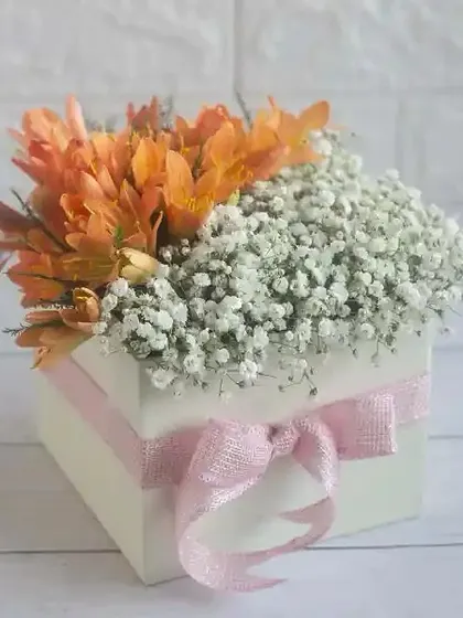 A charming box arrangement of orange lilies and baby's breath, a sweet and simple gift for someone special.
