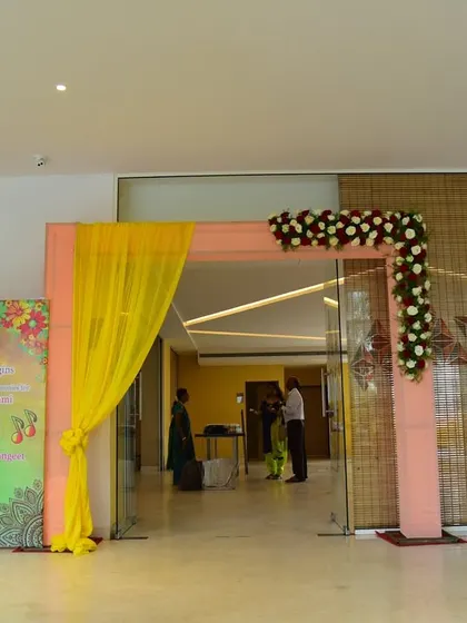 A simple entrance for a Haldi function in a hall, using bright yellow drapes and a custom welcome banner.
