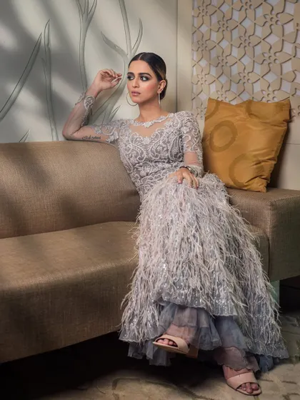 A sophisticated portrait of influencer Jumana Khan, ready for a Filmfare event. The focus is on the intricate details of her feathered gown and the glamorous makeup.