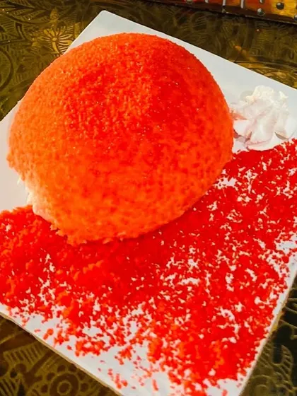 A vibrant Oozing Jelly Pastry, featuring a bright red dome on a decorative plate.