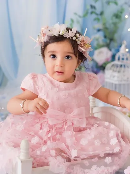 Another beautiful shot of the baby girl on her tiny white bed, looking directly at the camera with a curious expression.