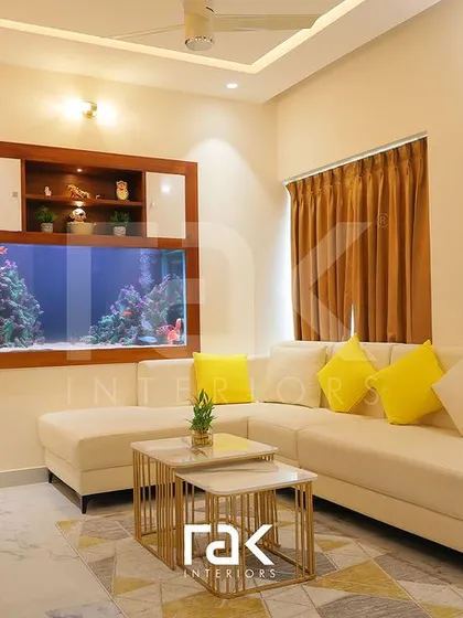 The living room in Mr. Yadhudas's villa, featuring a large, comfortable L-shaped sofa and a stunning built-in aquarium as a unique focal point.