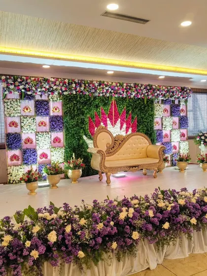 A beautiful stage with a floral wall featuring purple, pink, and white flowers in a geometric pattern.