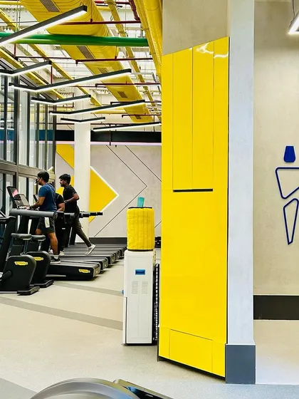 Functional design details in the Chennai gym, including integrated water coolers and clear signage. The consistent use of yellow and geometric lines ensures a cohesive and branded environment throughout the facility.